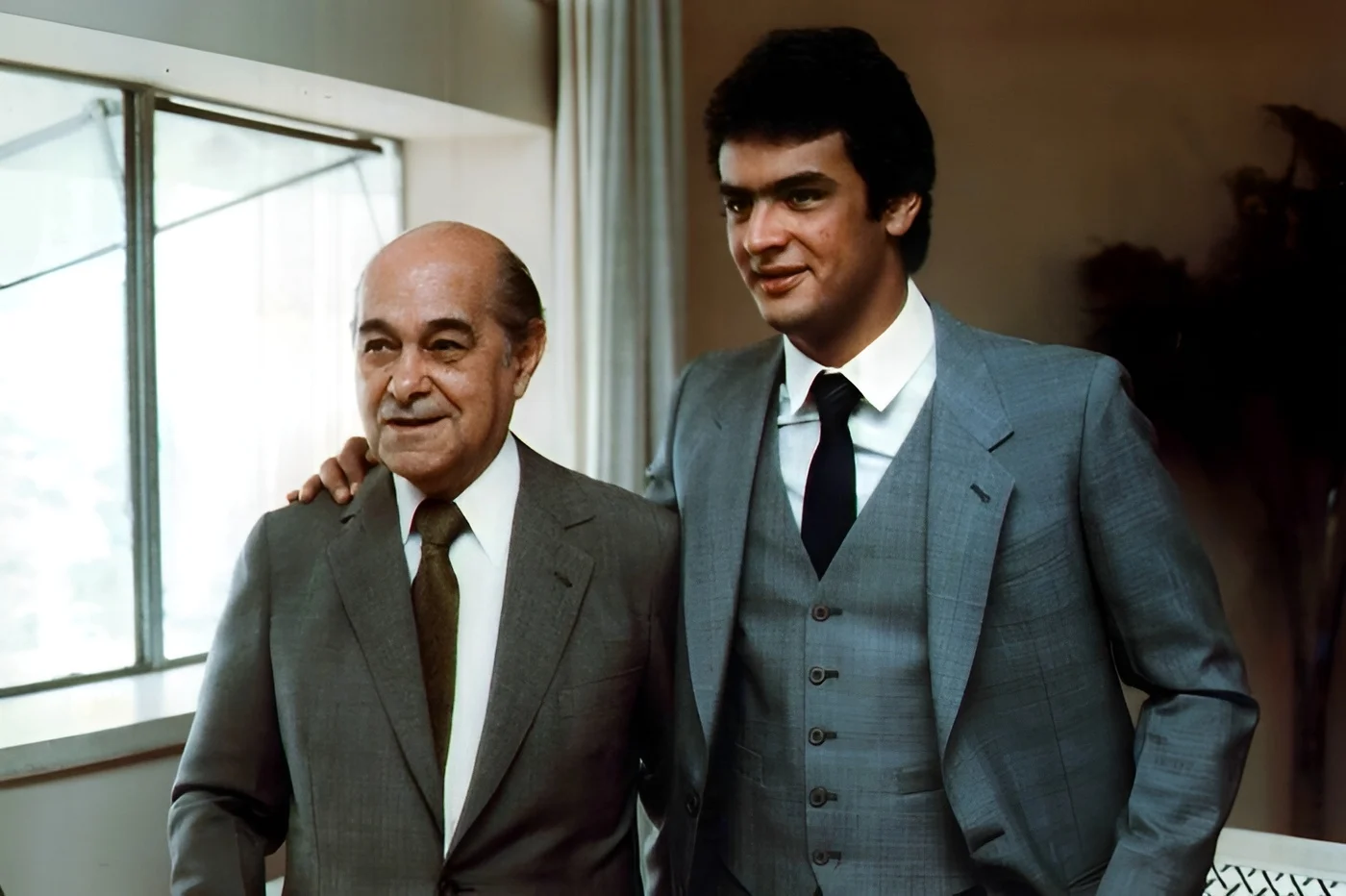 Aécio Neves ao lado de Tancredo Neves em imagem histórica familiar. A comparação reforça o debate sobre herança política e capital simbólico no caso de Flávio Bolsonaro.