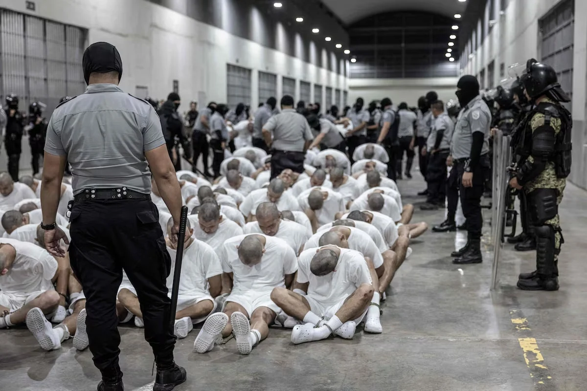 Detentos aparecem ajoelhados em prisão de segurança máxima em El Salvador usada no sistema de deportação ligado aos EUA.