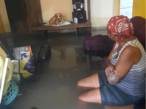 Moradora em casa inundada no Rio de Janeiro durante enchente que atingiu área urbana vulnerável.