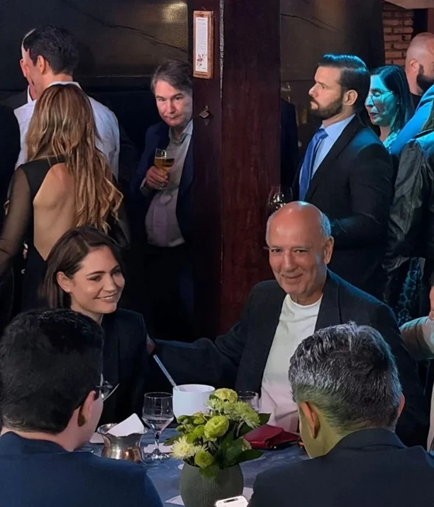 Michelle Bolsonaro sentada à mesa com Alberto Fraga durante evento político que reuniu lideranças do PL no Distrito Federal.