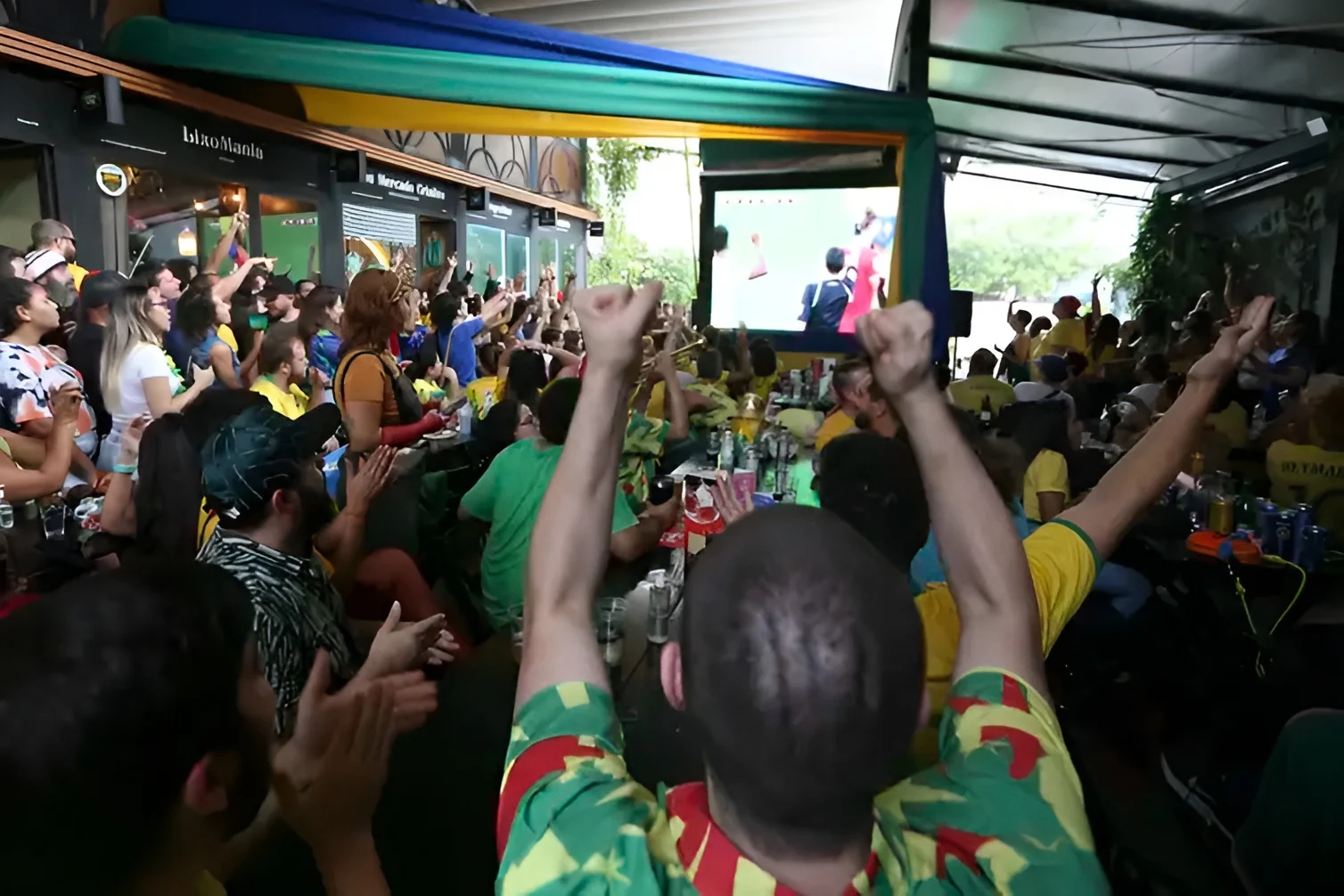 Torcedores celebram em ambiente público com euforia durante jogo de futebol. A imagem ilustra o argumento do artigo de que tanto a vitória quanto a derrota do time podem funcionar como gatilho para a violência doméstica contra mulheres — o ambiente de consumo de álcool e extravasamento emocional do futebol forma o coquetel de risco descrito pela autora.